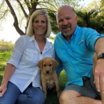 two people and a dog posing in front of trees