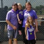 family posing outdoors in front of a fence